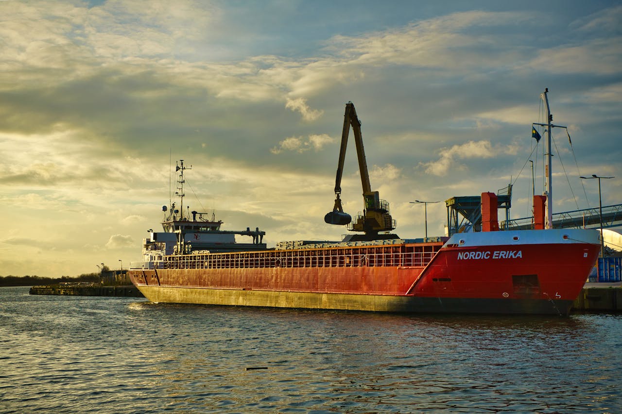 A vibrant red cargo ship named Nordic Erika moored at a harbor during a beautiful sunset.